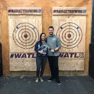 Diane and Ryan posing in front of plywood targets holding axes.